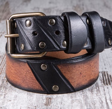 Cintura in cuoio marrone e nero di MaxCuoio con inserti di chiodi arrotolata su un tavolo