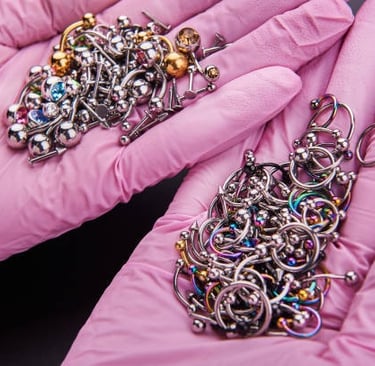 Hands in pink gloves holding assorted piercing jewellery at Piercing by Jooles Montrose