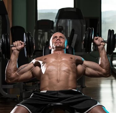A man performing a dumbbell incline chest press exercise in a gym