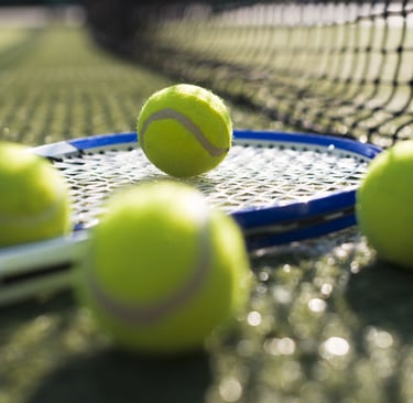 Raqueta y pelotas de tenis en cancha de tenis