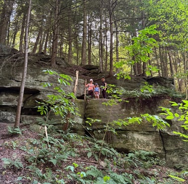 a group of children standing on a rock formation while hiking in Cuyahoga Valley National Park