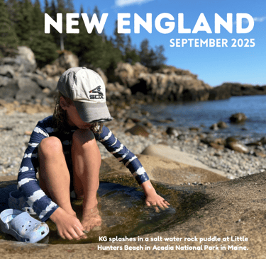A young girl plays in a puddle on a rock by the ocean coast