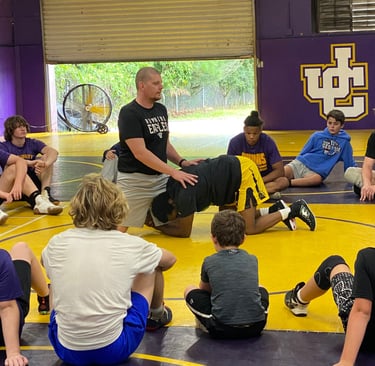 a group of people sitting on a wrestling mat