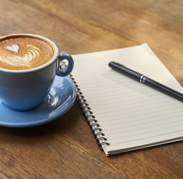 a cup of coffee with a pen and a notebook