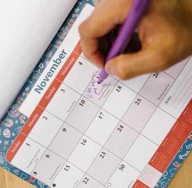 a person holding a pen and writing on a calendar