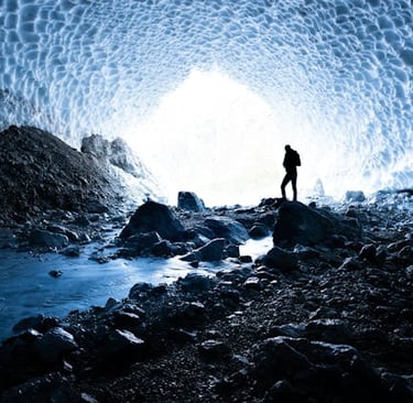 a person standing in a cave with a view of a glacier