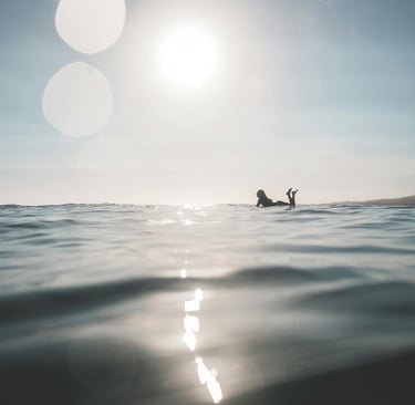 a person laying on a surfboard in the ocean