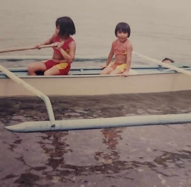 My sister and I on a tropical boat in the water as children.