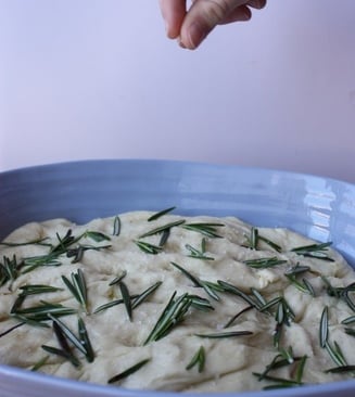 salt being added to the uncooked dough of rosemary focaccia bread