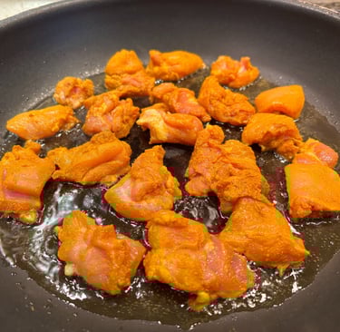 chopped marinated chicken thighs frying in pan
