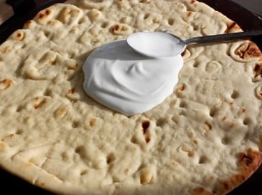 coconut milk being spread on pizza dough