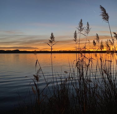 Sunset over Lake Oggiono with warm reflections on the water."