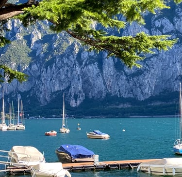 Sailboats gliding on Lake Como with mountains in the background.