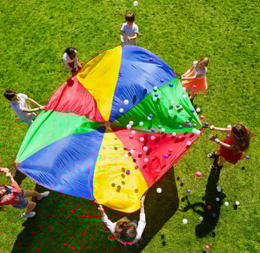 a group of people playing with a giant colorful umbrella