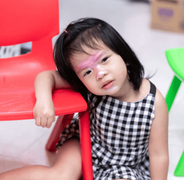 a little girl with a pink face paint on her face