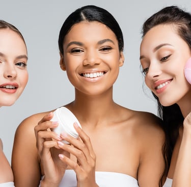 como elegir el facial ideal segun tu tipo de piel, grupo de tres mujeres con rodillo de jade, crema y dispositivo limpiador f