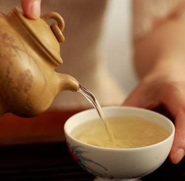 The teapot pouring tea into the teacup