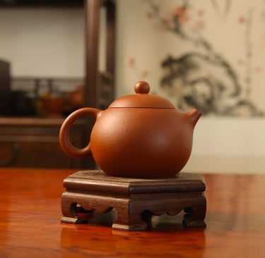 Round-shaped teapot placed on a wooden stand