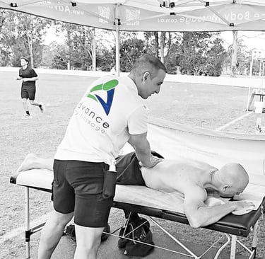 Male massage therapist performing remedial massage on a males back