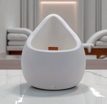 Image shows a candles with a wooden wick in a white container with form of a drop. 
