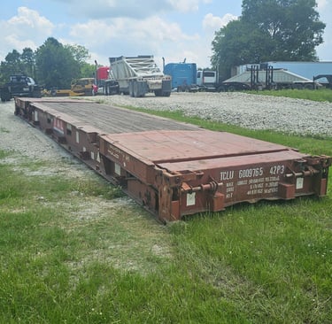 A red 40ft flat rack laying on the ground
