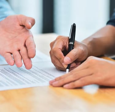 Trata-se de duas mãos, uma assinando um contrato e outra validando a assinatura.