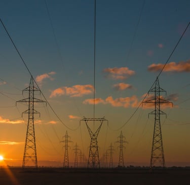 Trata-se de um campo com um por do sol com torres de energia 