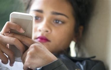 Mädchen schaut konzentriert auf ihr Smartphone.