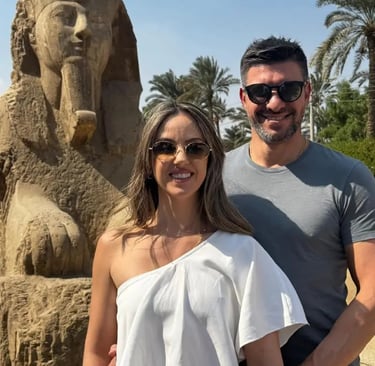 casal de turistas de brasil frente de estatua de esfinge de marmore em memfis com o guia hadi salah