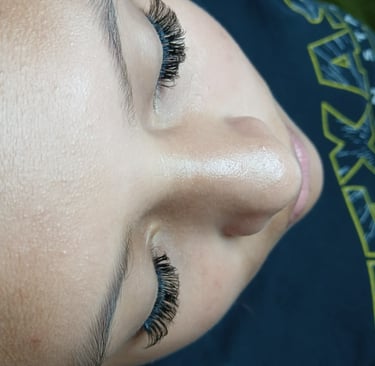 Close-up of a woman's face showing professional volume eyelash extensions with a natural curl.