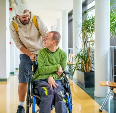 NDIS support worker assisting a man in a wheelchair in a bright, modern hallway