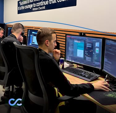 Team members working at dual-monitor workstations in a modern office environment, with a motivationa