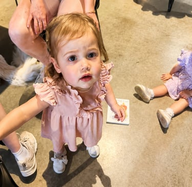 Two toddler girls in dresses playing during a family gathering