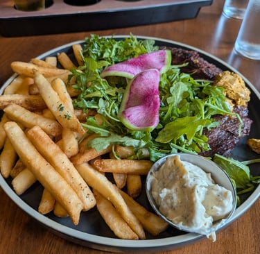 Steak frites platter served with crispy golden french fries, fresh arugula salad, and creamy dipping sauce.