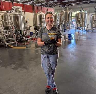 a woman standing in front of brewing tanks