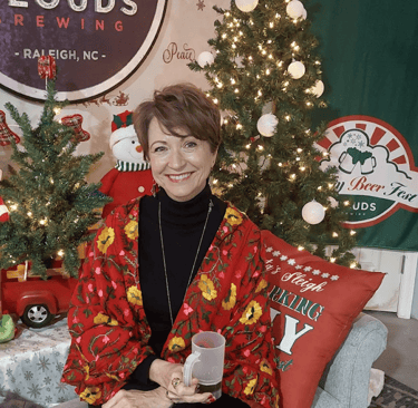 a woman in a red jacket is holding a glass of beer in a seasonal setting