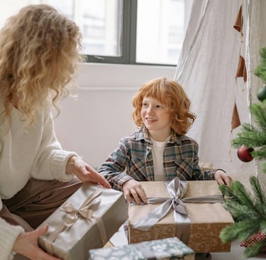 Mother giving her daughter a gift under Christmas tree