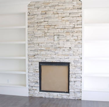 a white fireplace with stone facing and shelves
