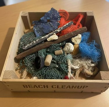 A wooden crate labeled beach cleanup filled with plastic waste, fishing nets, and ocean debris.
