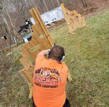 Kneeling man engaging targets from a barrier using self-defense firearm during training.