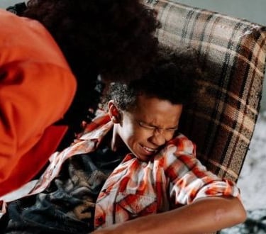 a woman sitting on a chair with a man in a red shirt