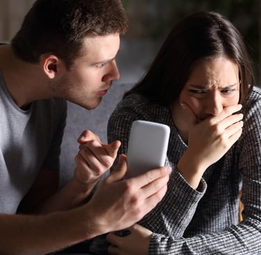 a man and woman sitting on a couch looking at a cell phone