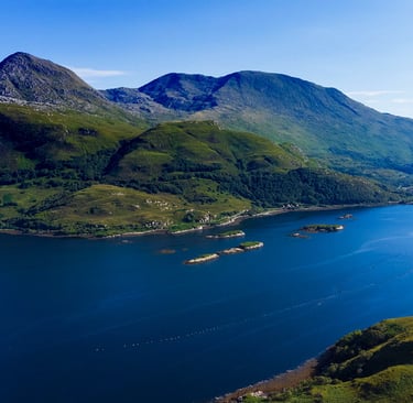 Aerial view of a scenic blue sea loch surrounded by green mountains in the Scottish Highlands.