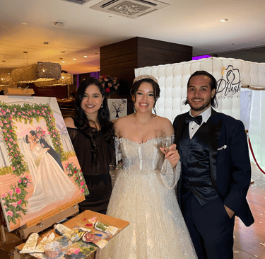pareja de esposos posando junto a la pintora y su obra de arte en una boda en panama