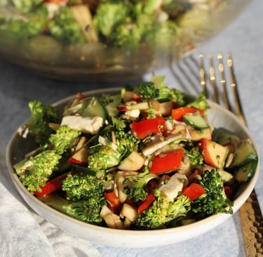 a bowl of broccoli salad with apple and broccoli