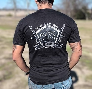 a man in a black shirt and jeans standing in a field