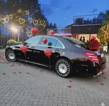 Luxury black Mercedes sedan decorated with red heart balloons and rose petals for a romantic evening event.