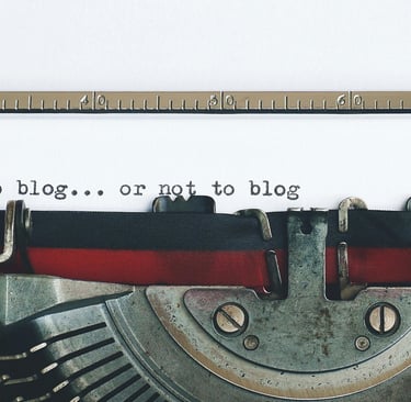 The top of a black and red typewriter, with the words "to blog... or not to blog" already typed.