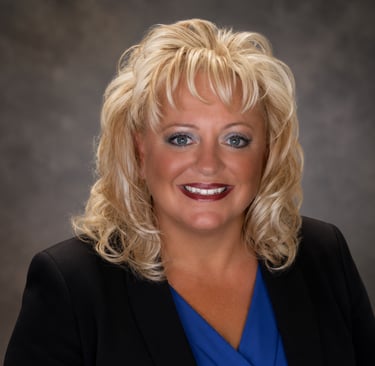 Professional headshot of a JoJo Caruana businesswoman in a black blazer and blue blouse.