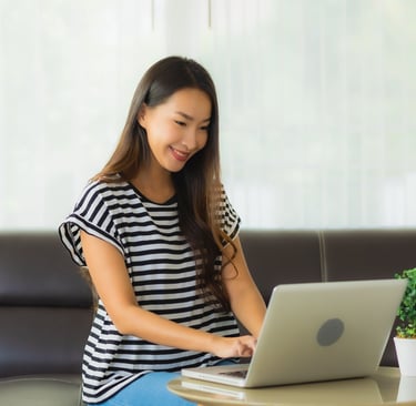 a woman sitting on a couch searching for job opening on her laptop